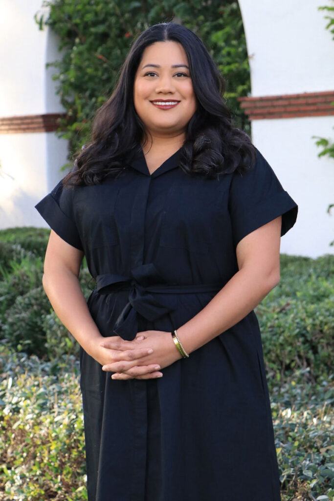 Jessie Lopez in black clothing, smiling and standing with her hands folded.