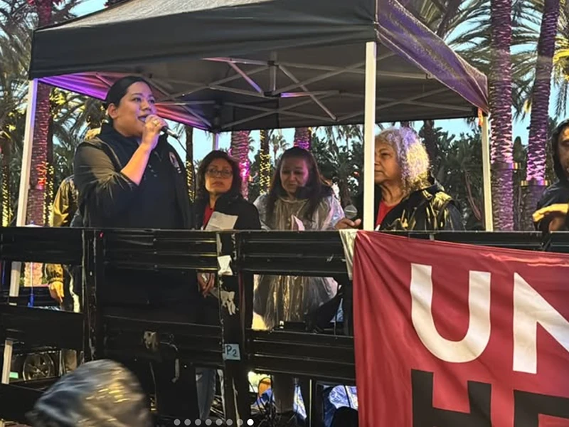 Jessie Lopez speaking on a microphone under a canopy during a strike.