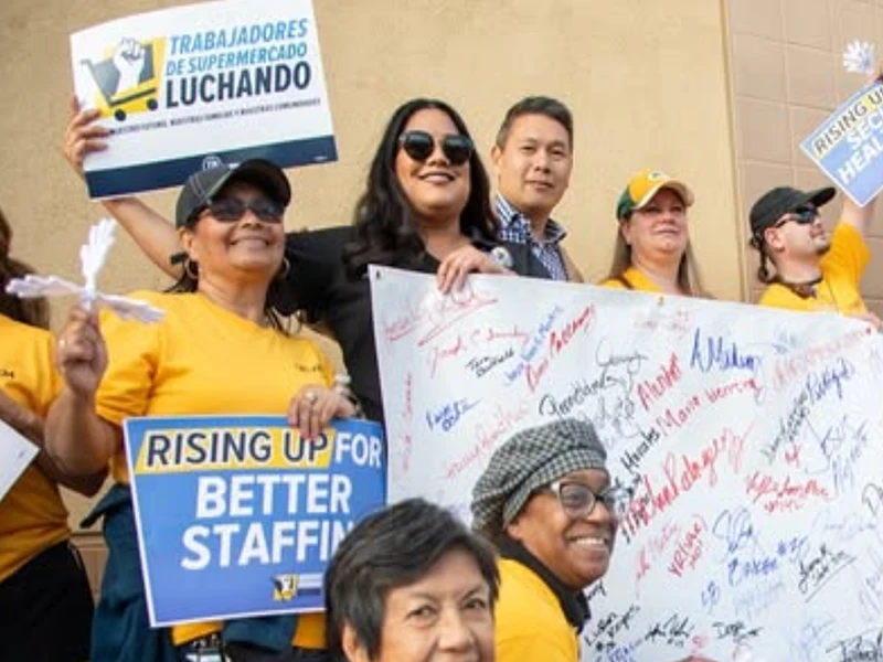 Jessie Lopez standing with striking UFCW grocery workers holding a sign.