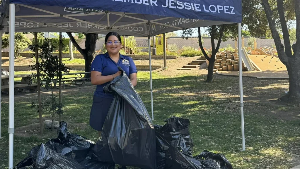 Councilwoman Jessie Lopez putting trash into a large black bag at a Santiago Park cleanup she hosted.