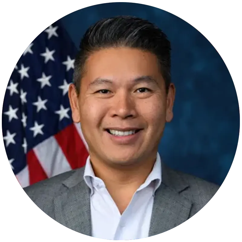 Congressman Derek Tran smiling in front of an American flag.
