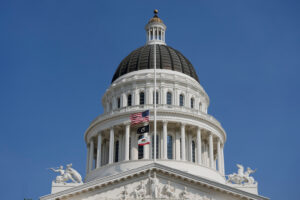 Looking up at the Sacramento Capitol building over a blue sky.