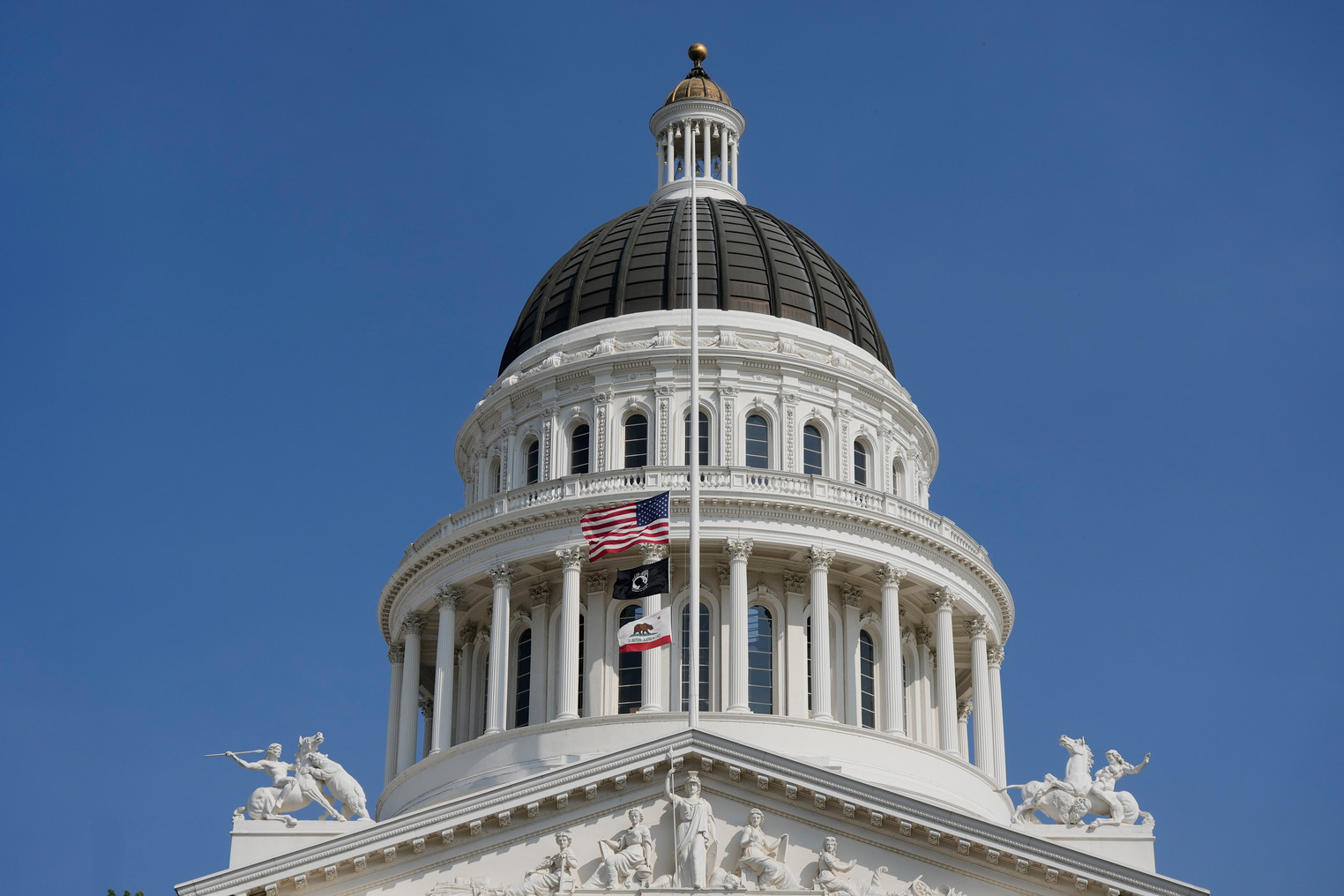 Looking up at the Sacramento Capitol building over a blue sky.